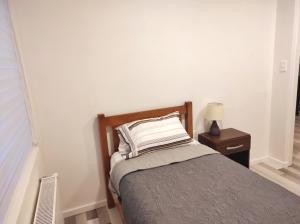 1 dormitorio con cama con almohada y mesita de noche en Casa nueva, excelente ubicación en Punta Arenas