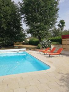 een zwembad met twee oranje stoelen naast bij Au Doux Repos in Lucbardez-et-Bargues