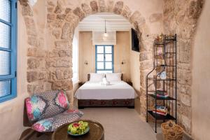 a bedroom with a bed and a chair and a table at Arabesque House in ‘Akko