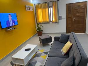 a living room with a couch and a tv on a yellow wall at Gîte Le Toubé in Saint-Louis