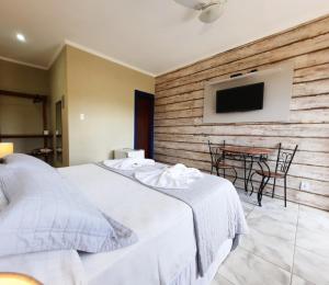 a bedroom with a bed and a table with chairs at Pousada Luz do Sol in Carrancas