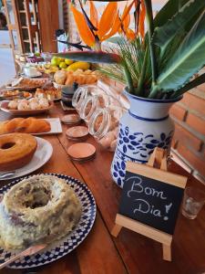 a table topped with plates of donuts and a sign at Pousada Luz do Sol in Carrancas