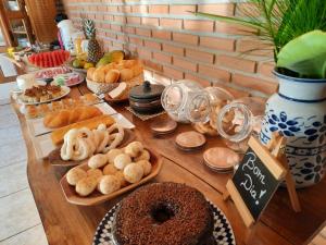a table topped with different types of bread and pastries at Pousada Luz do Sol in Carrancas