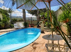 a swimming pool in a yard with a table and chairs at Pousada Luz do Sol in Carrancas