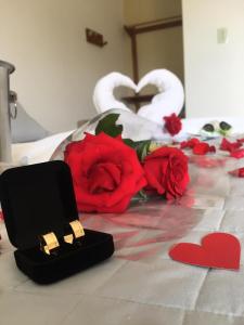 a bed with red roses and two hearts and two swans at Pousada Luz do Sol in Carrancas