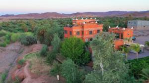 an orange building in the middle of a field with trees at Riad Chay & Boutique in Ouarzazate