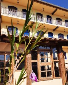 a purple flower in front of a building at Pousada Luz do Sol in Carrancas