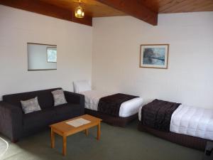 Habitación con 2 camas, sofá y mesa. en Coachman's Lodge Motel, en Whanganui