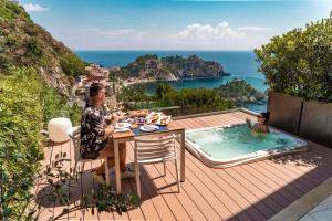 un homme assis à une table à côté d'une piscine dans l'établissement Isola Bella Infinity Suites, à Taormine