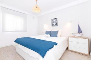 biała sypialnia z niebieskim kocem na łóżku w obiekcie Huelin Beach & Sun w Maladze