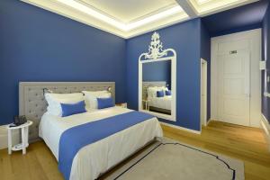een blauwe slaapkamer met een bed en een spiegel bij EMAJ Boutique Hotel in Guimarães