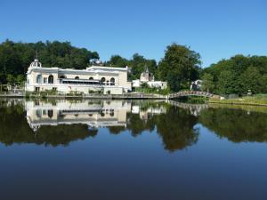 a white building on the water with a bridge at appartement au Hameau du parc des thermes in Bagnoles de l'Orne