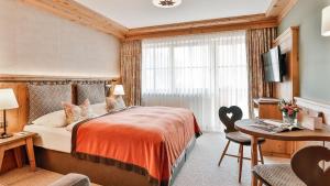una camera d'albergo con letto, scrivania e TV di Superior Hotel Tirolerhof - Zell am See a Zell am See