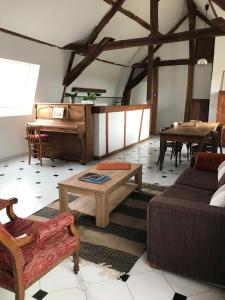 a living room with a couch and a piano at La Barcelle, une pause nature. in Perrigny