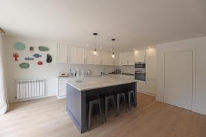 a kitchen with white cabinets and a large island with stools at FLH Serralves House with Garden in Porto