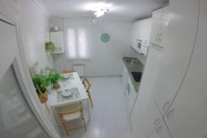 una cucina bianca con tavolo e piano di lavoro di Apartamento en el centro de Mundaka EBI646 a Mundaka