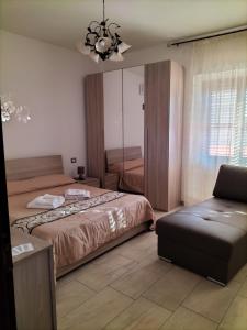 een slaapkamer met 2 bedden, een bank en een kroonluchter bij B&b la Fenice in Terralba