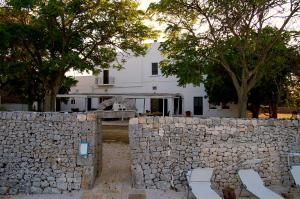 un mur en pierre devant une maison blanche dans l'établissement B&B Masseria Santanna, à Monopoli