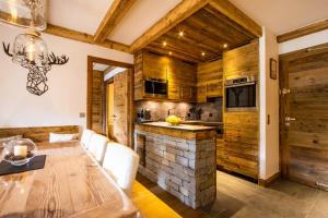 a dining room with a table and a kitchen with wooden walls at Arc 1950, ambiance chalet luxe 5/7pers dans résidence 5* skis aux pieds avec SPA in Arc 1950