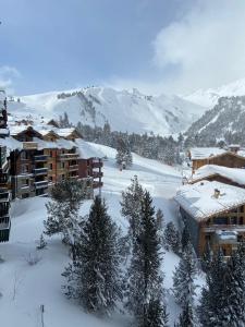 a resort in the snow with trees and buildings at Arc 1950, ambiance chalet luxe 5/7pers dans résidence 5* skis aux pieds avec SPA in Arc 1950