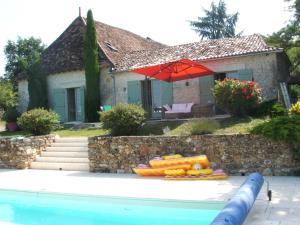 a house with a swimming pool and a red umbrella at La Zénitude in Les Lèches