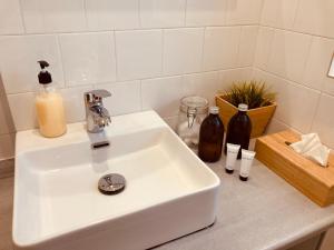 a white sink sitting on a counter with bottles of soap at 21 Suites Deluxe Stay Near The Airport in Markopoulo