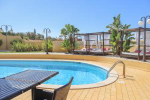 a swimming pool with a table and chairs in a resort at Quinta Nova Vale Del Rey in Carvoeiro