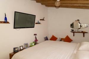 a bedroom with a white bed and a flat screen tv at Ideal y linda casita en San Cristóbal-Galápagos in San Cristóbal