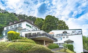 un hotel con un edificio blanco y árboles en Waldhotel Soodener-Hof, en Bad Sooden-Allendorf