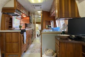 a large kitchen with wooden cabinets and a tv at Beautiful Airstream, Beaufort SC-Enjoy the Journey in Beaufort