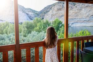 a little girl standing on a porch looking out at the mountains at Camping Port Massaluca in Pobla de Masaluca