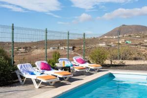 a group of chairs sitting next to a swimming pool at Apartment Private Heated Pool in El Draguito