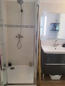 a white bathroom with a shower and a sink at Appartement dans la verdure près des plages in Saint-Cyprien-Plage