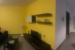 uma sala de estar com um sofá e uma parede amarela em The Overhills Suite, your home away from home em Naxxar