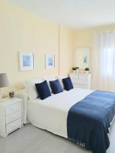 biała sypialnia z dużym łóżkiem z niebieskimi poduszkami w obiekcie Vistamar Blue w Aronie