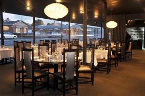 un comedor con mesas, sillas y luces en Auto Lodge en New Plymouth