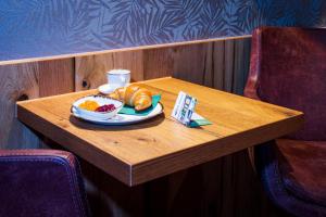 einen Tisch mit einem Teller Brot und einer Tasse Kaffee in der Unterkunft Kb Hotel in Nersingen