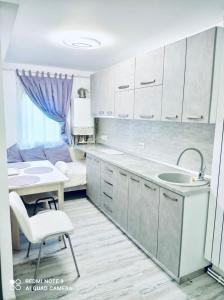a kitchen with white cabinets and a table and a sink at Garsonieră Daniela in Târgu Ocna