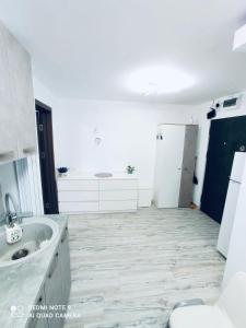 a white bathroom with a sink and a toilet at Garsonieră Daniela in Târgu Ocna
