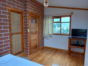 a room with a brick wall and a television at Bonanza Hospedaje in Otavalo