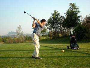 un hombre balanceando un palo de golf en un campo en Il Giardino degli Ulivi, en Corpolò