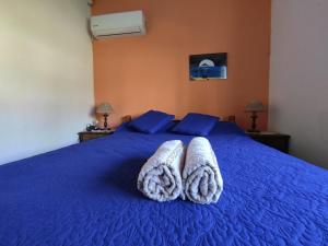 Un dormitorio con una cama azul con toallas. en GUSMAR - Hermosa y confortable casa a pasos de la playa., en Santa Ana