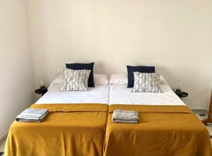duże łóżko z żółtą pościelą i dwoma ręcznikami w obiekcie Apartamento Bahía Jardín w mieście La Herradura