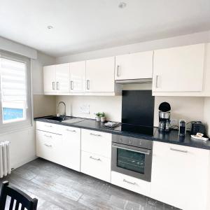 a kitchen with white cabinets and a black counter top at La Capitainerie in Cancale