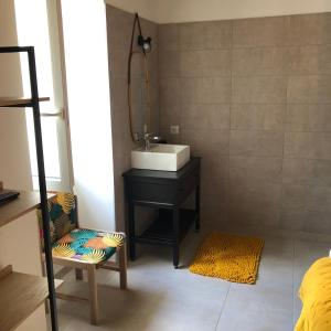 uma casa de banho com um lavatório, um espelho e uma cadeira em Manoir de Champvert em Les Vans