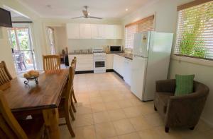 a kitchen and dining room with a table and a refrigerator at The Palms At Avoca in Avoca Beach
