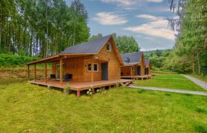 a log cabin with a large deck in the grass at Domki Bieszczady - Baza uŚmiechów in Ustrzyki Dolne