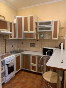 uma cozinha com armários brancos e uma mesa com cadeiras em Apartment Miskevycha em Lviv