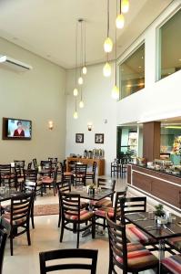 a restaurant with tables and chairs and a bar at Hotel Matão By Mercure in Matão