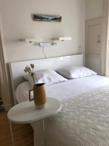 a white bed with a table with a vase on it at GUESTHOUSE UIT DE KUNST in Leeuwarden